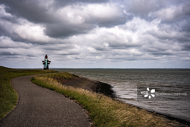 朋友们背对着镜头站在路上，背景是多云的天空，地点：荷兰泽兰省科林斯普拉特。图片素材