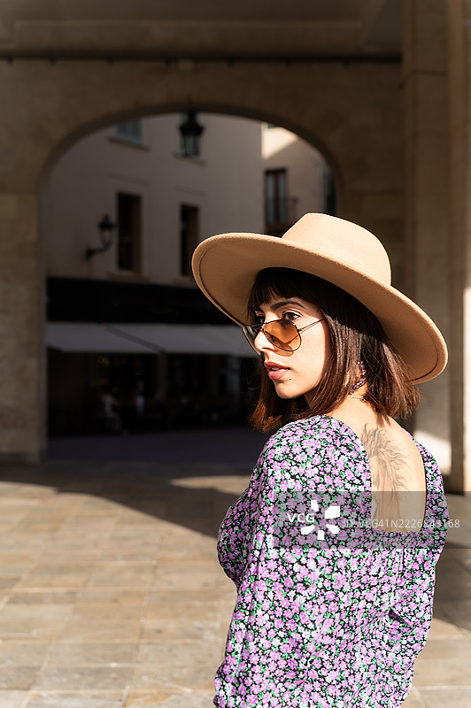 时尚年轻女性戴着帽子和太阳镜在欧洲城市探险图片素材