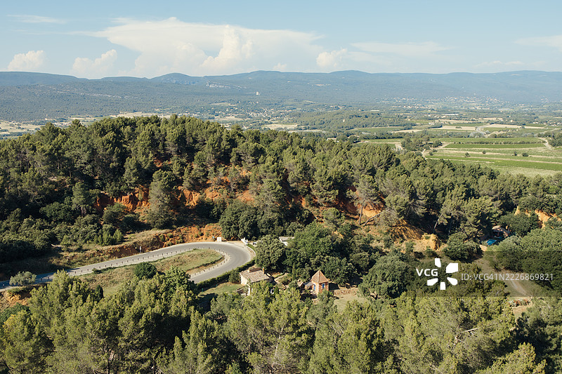 蜿蜒的道路穿过郁郁葱葱的森林，展现出如画的鲁西永风景图片素材