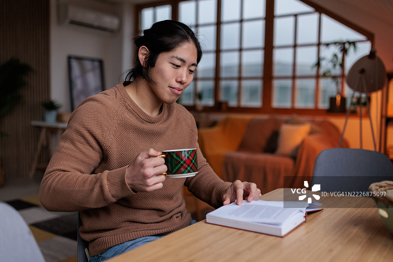 日本男子在家中悠闲地品茶阅读好书图片素材
