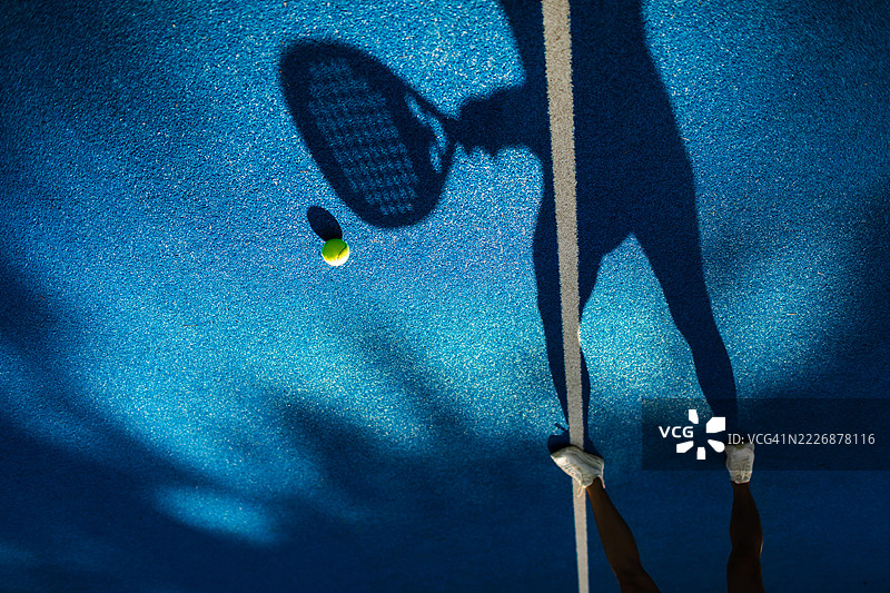 蓝色球场上网球拍的影子与网球图片素材