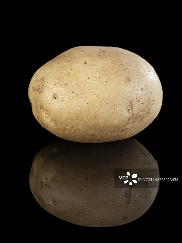 整个生土豆在黑色背景上的倒影。图片素材
