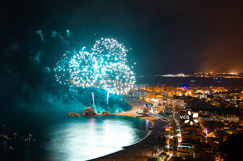 节日夏季庆典期间，绚丽的烟花在充满活力的海滨城市景观上空绽放图片素材
