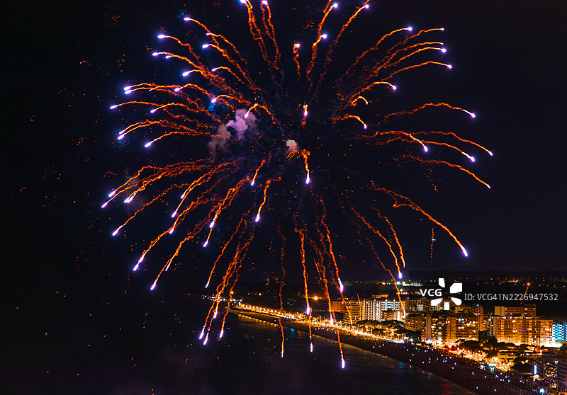 地中海夏季节日中，金色的烟花在黑暗的天空中如棕榈树般绽放。图片素材