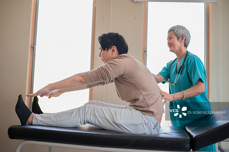物理治疗师正在为男性的背部进行康复治疗。背痛患者，治疗的库存照片图片素材
