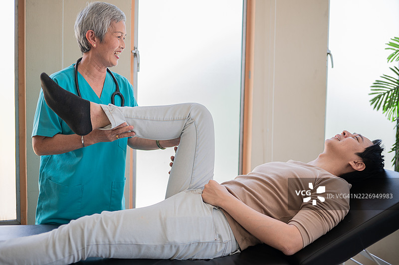 物理治疗医生、患者与腿部手术、物理治疗和骨科康复。物理治疗师、脊椎按摩师、伤害、骨质疏松症和关节炎康复的库存照片。图片素材