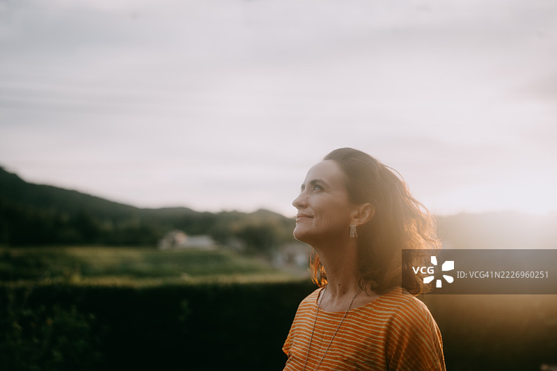 在日本千叶的乡村，女人仰望日落。图片素材