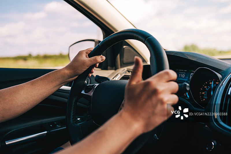 阳光明媚的日子里，手握方向盘的特写镜头图片素材