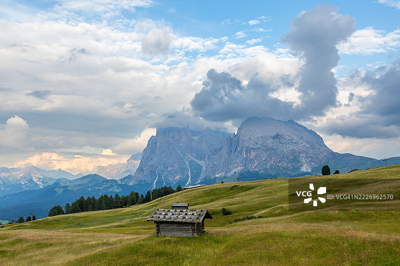 多洛米蒂山脉的风景，带有一座乡村小屋和多云的山脉。塞尔瓦阿尔姆图片素材