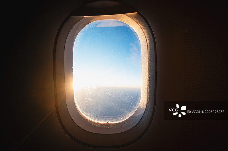 阳光透过飞机窗户洒在云层上，展现出美丽的飞行景色图片素材