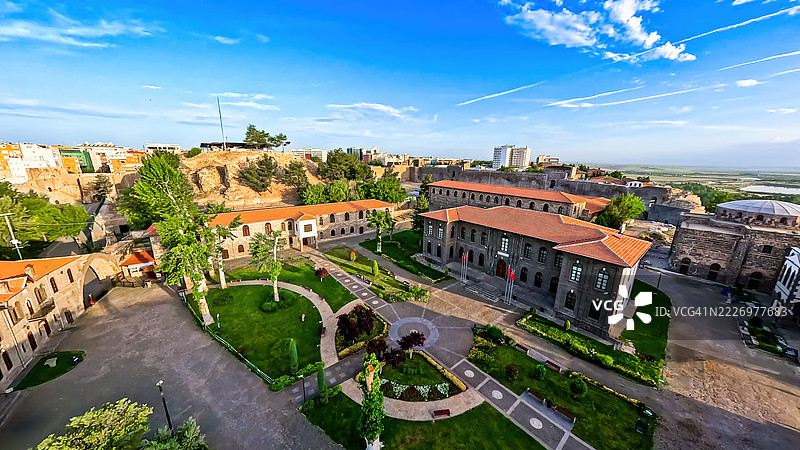 夕阳下的迪亚巴克尔城市天际线和古老的城墙的FPV航拍视角，历史清真寺的尖塔高耸于修复的奥斯曼建筑之上，展示了东南土耳其的文化遗产和旅游目的地。图片素材