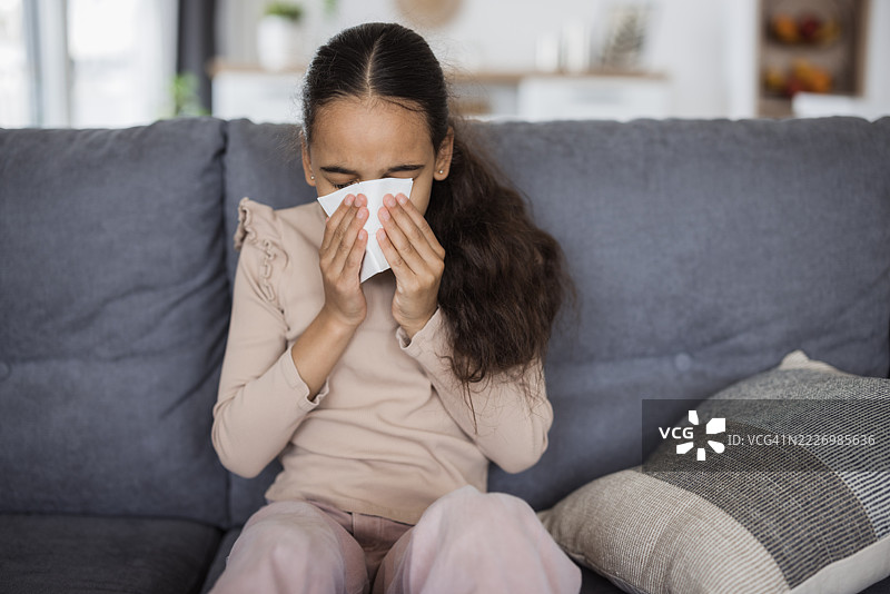 生病的儿童在沙发上擤鼻涕图片素材