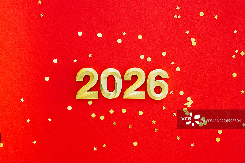 红色背景上方视角的金色数字2026，周围有金色的五彩纸屑。节日新年贺卡。图片素材
