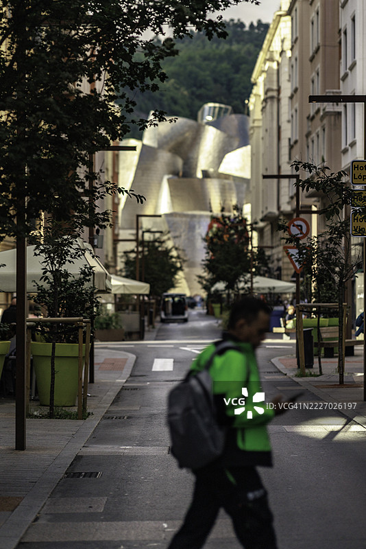 在古根海姆博物馆前穿行的男子图片素材