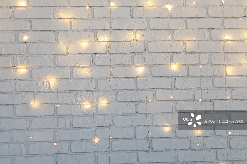 白色砖墙上点缀着许多小小的仙女灯，柔和地照亮了整个表面。图片素材