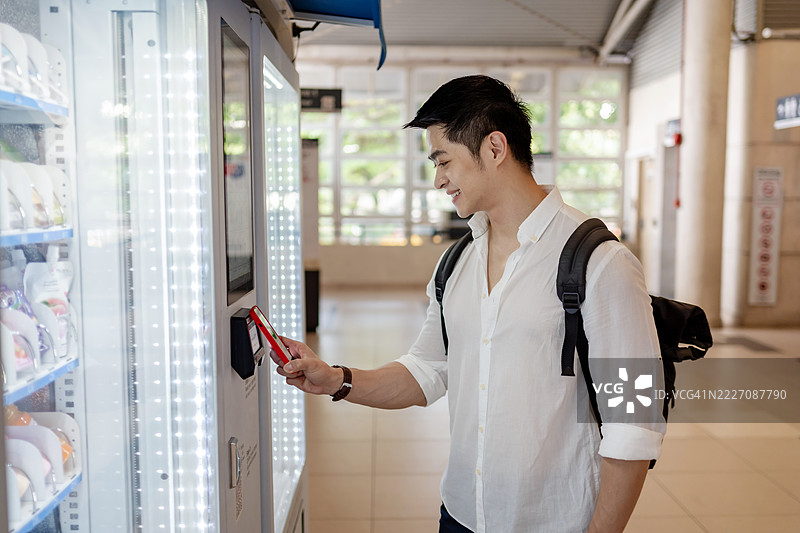 男子用手机在自动售货机付款图片素材