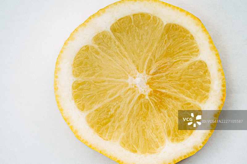 一片柠檬的特写展示了其鲜艳的黄色果肉和厚厚的果皮，背景简约。图片素材
