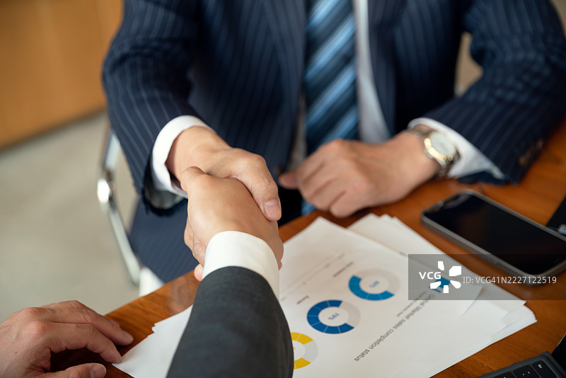 商务人士在现代办公室握手。图片素材