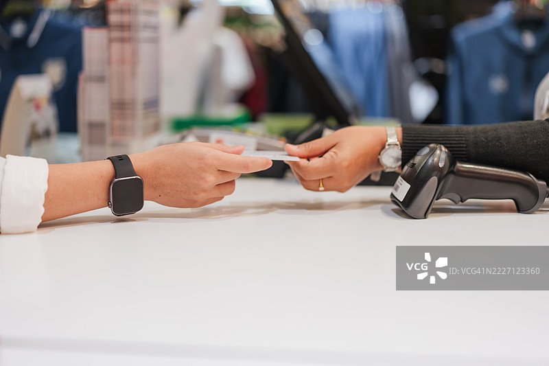 顾客在零售结账柜台将信用卡递给收银员的特写，强调无接触购物、金融和现代支付方式。图片素材