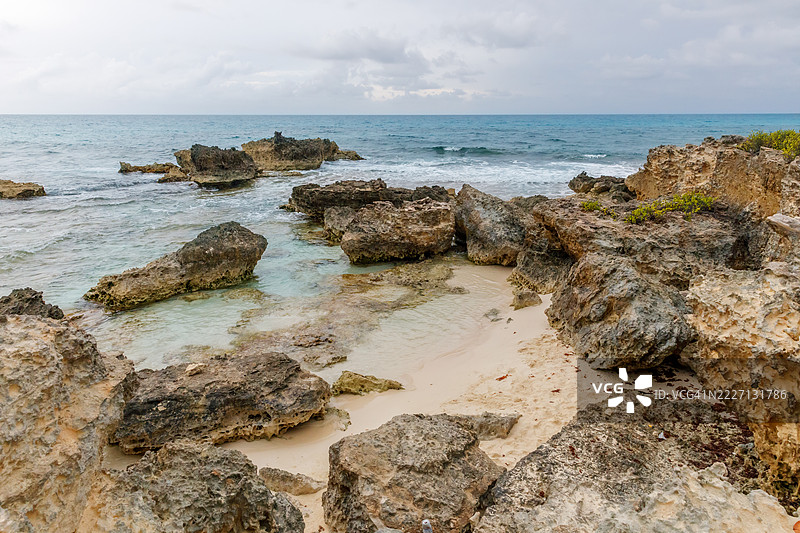 墨西哥北部穆赫雷斯岛的岩石海岸线，碧蓝的海水和阴云密布的天空图片素材