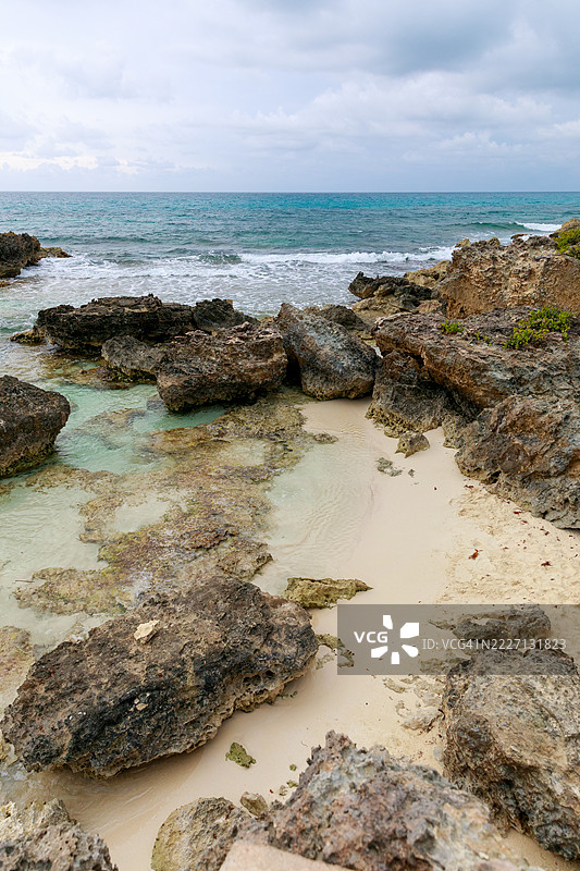 墨西哥北部穆赫雷斯岛的岩石海岸线，碧蓝的海水和阴云密布的天空图片素材