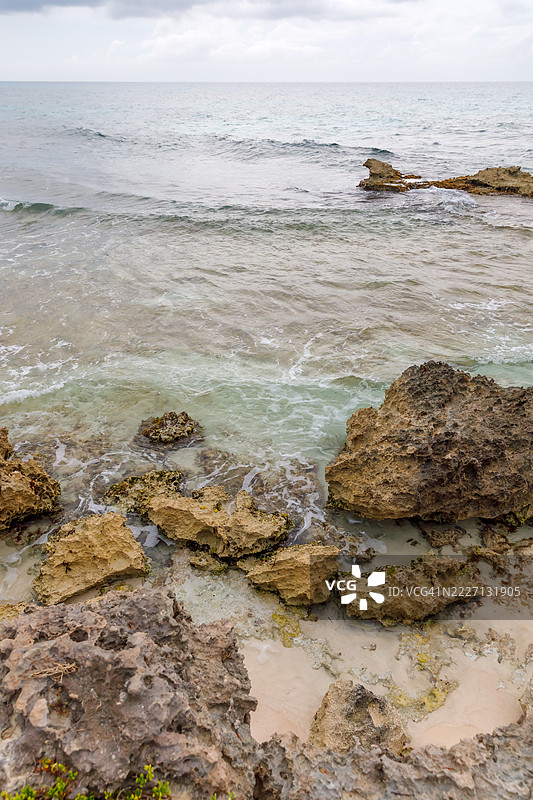 墨西哥北部穆赫雷斯岛的岩石海岸线，碧蓝的海水和阴云密布的天空图片素材