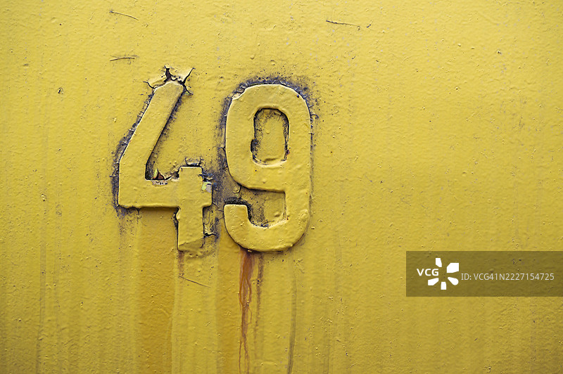 在一块显示出老化迹象的黄色金属表面上压印的数字四十九图片素材