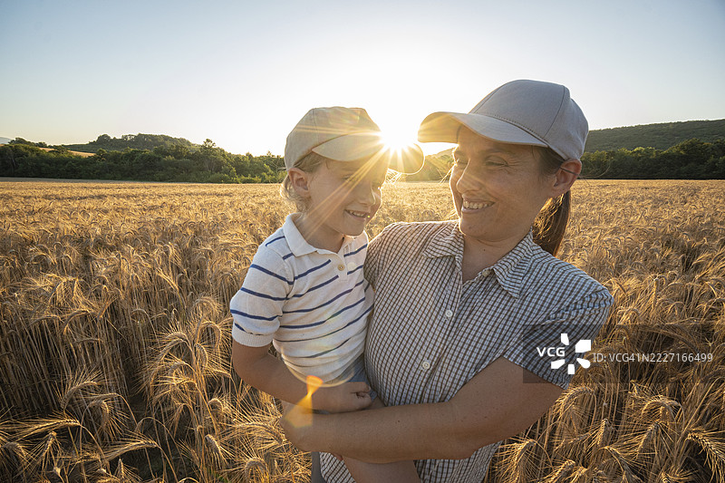可持续农业。农民家庭在日落时分的小麦田里图片素材