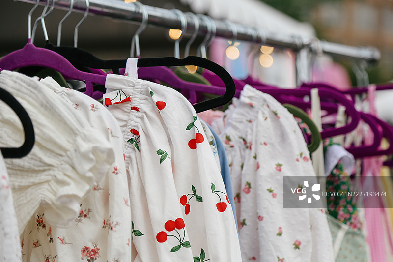 全景展示夏季柔和色彩的棉质连衣裙、上衣和裙子，挂在服装市场的衣架上进行促销。图片素材