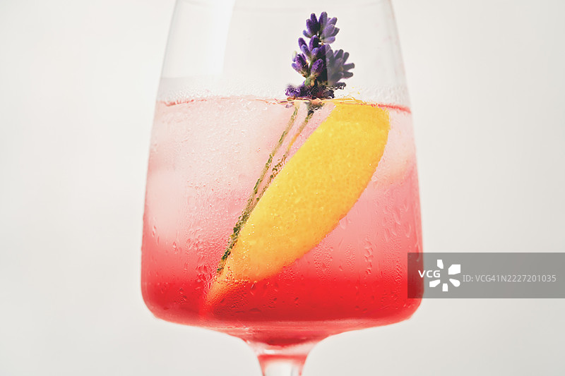 夏天桌子上的一杯柠檬气泡鸡尾酒特写。带有薰衣草花装饰的出汗酒杯。图片素材