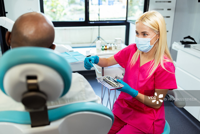 牙医戴着手术口罩和手套，正在拿起牙科工具图片素材