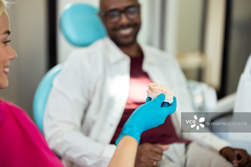 牙医向患者展示牙齿模型图片素材