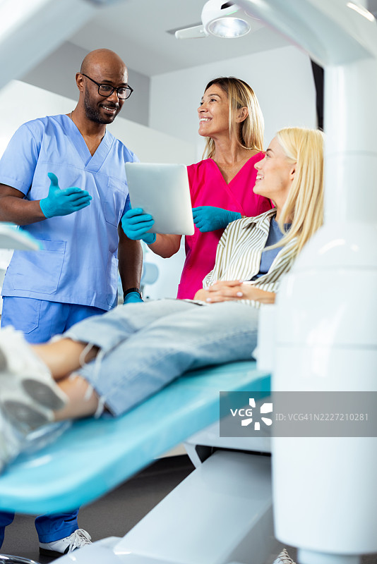 牙医和护士在牙科办公室向患者展示平板电脑上的结果图片素材