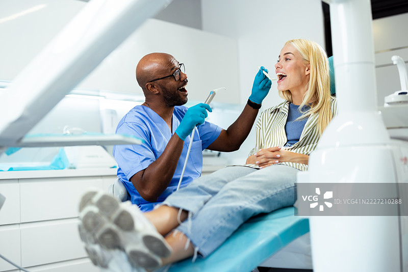 牙医在现代诊所使用牙科设备检查病人的牙齿图片素材