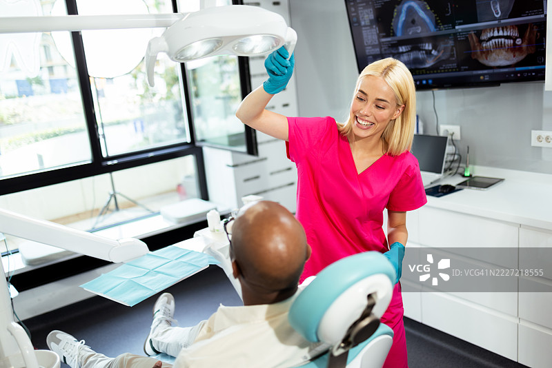 牙医在牙科诊所为病人调整灯光图片素材