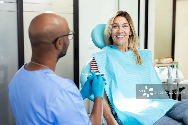牙医在诊所向患者展示牙科设备图片素材
