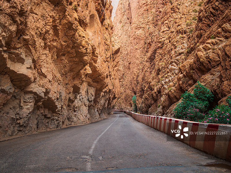 宽广的视角展示了一条笔直的空旷道路,两旁是安全护栏,标记着著名的达德斯河峡谷,这是阿特拉斯山脉中的自然地标,进入峡谷的狭窄通道,布马尔内·达德斯 - 蒂内里赫 - 德拉·塔菲拉勒 - 摩洛哥。图片素材