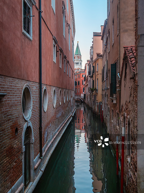 圣马可大钟楼在平静的运河（圣萨尔瓦多河）水面上的倒影，运河两旁是带有舷窗的住宅建筑，位于威尼斯的圣马可区，日出时分，联合国教科文组织世界遗产 - 威尼托 - 意大利。图片素材