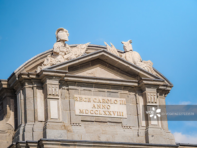 阿尔卡拉门(Puerta de Alcalá)山花的特写,位于马德里独立广场(Plaza de la Independencia),是一座被列为胜利拱门和城市大门的建筑,门前有两名倒下的士兵,佩戴着旗帜和头盔,旁边有拉丁文铭文 - 西班牙。图片素材