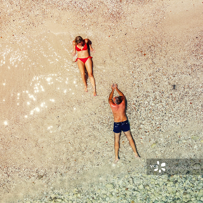 从空中俯瞰一对情侣躺在沙滩上图片素材