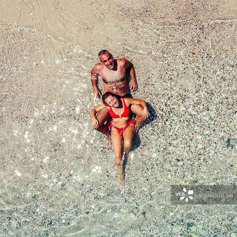 从空中俯瞰一对情侣躺在沙滩上图片素材