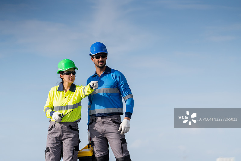 一名服务工程师正在检查屋顶太阳能电池板的维护情况，并检查是否有任何损坏的部件。该技术人员还参与太阳能电池板的安装，推广清洁能源的使用。图片素材
