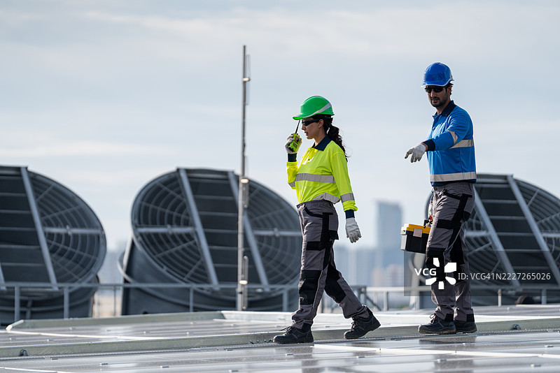 服务工程师正在检查屋顶太阳能电池板的维护情况，并检查是否有损坏的部件。技术人员还参与太阳能电池板的安装，推广清洁能源的使用。图片素材