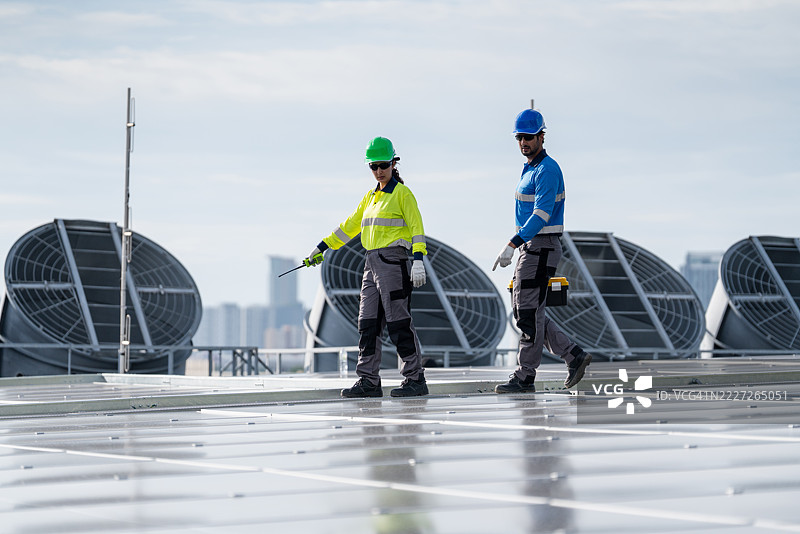 服务工程师正在检查屋顶太阳能电池板的维护情况，并检查是否有损坏的部件。技术人员还参与太阳能电池板的安装，推广清洁能源的使用。图片素材