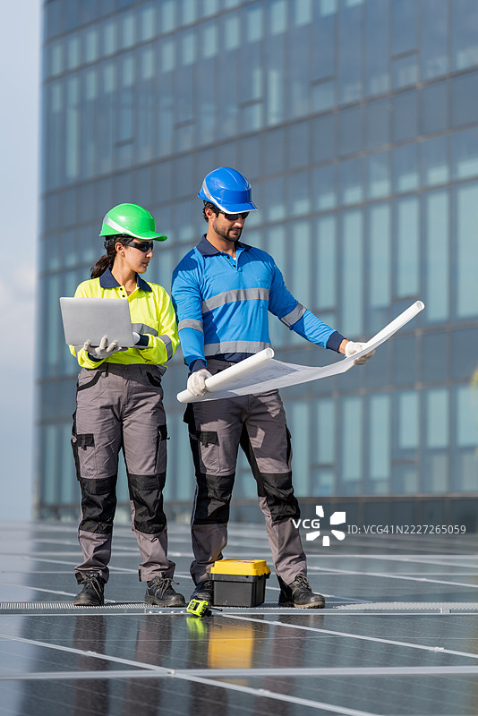 服务工程师正在检查屋顶太阳能电池板的维护情况，并检查是否有损坏的部件。技术人员还参与太阳能电池板的安装，推广清洁能源的使用。图片素材