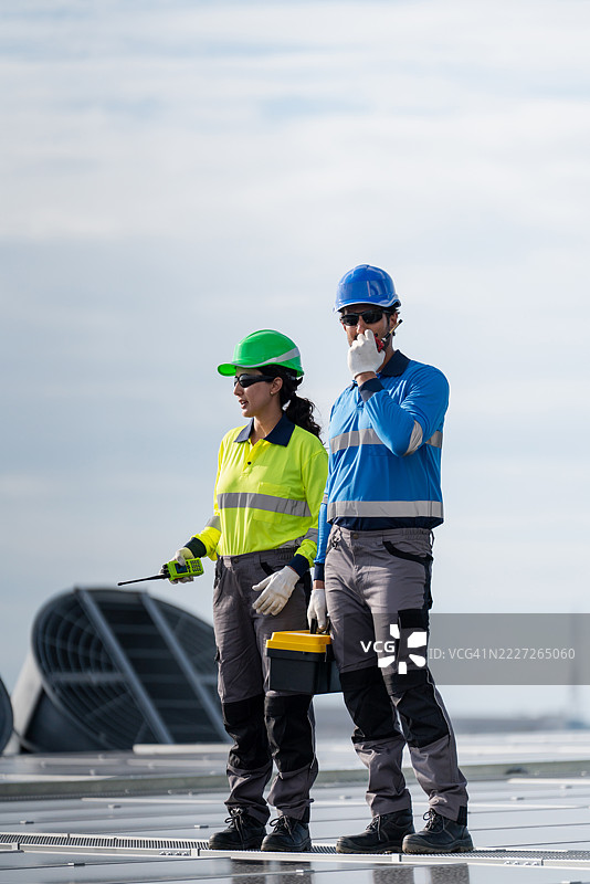 服务工程师正在检查屋顶太阳能电池板的维护情况，并检查是否有任何损坏的部件。技术人员还参与太阳能电池板的安装，推广清洁能源的使用。图片素材