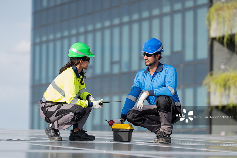 服务工程师正在检查屋顶太阳能电池板的维护情况，并检查是否有任何损坏的部件。技术人员还参与太阳能电池板的安装，推广清洁能源的使用。图片素材
