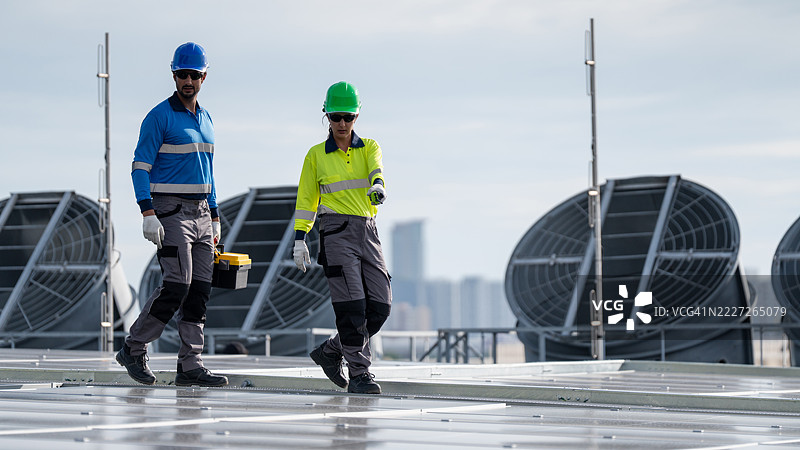 服务工程师正在检查屋顶太阳能电池板的维护情况，并检查是否有任何损坏的部件。技术人员还参与太阳能电池板的安装，推广清洁能源的使用。图片素材