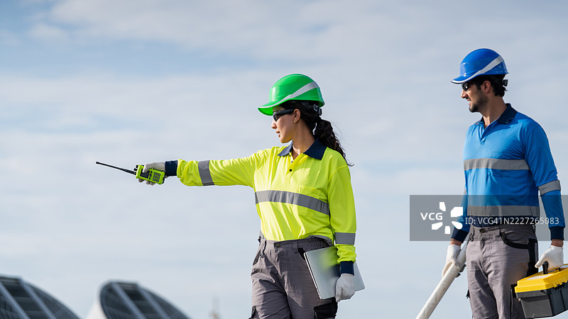 服务工程师正在检查屋顶太阳能电池板的维护情况，并检查是否有任何损坏的部件。技术人员还参与太阳能电池板的安装，推广清洁能源的使用。图片素材