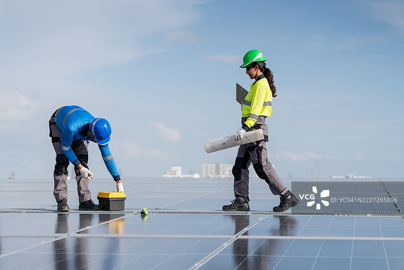 服务工程师正在检查屋顶太阳能电池板的维护情况，并检查是否有损坏的部件。技术人员还参与太阳能电池板的安装，推广清洁能源的使用。图片素材